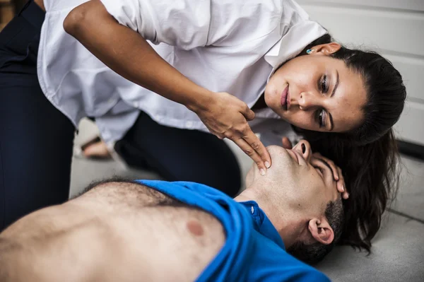 Girl assisting an unconscious man with defibrillator and CPR