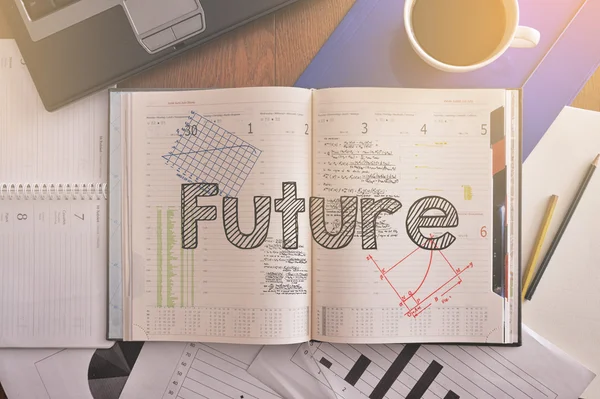 Notebook with text inside Future on table with coffee and some diagrams