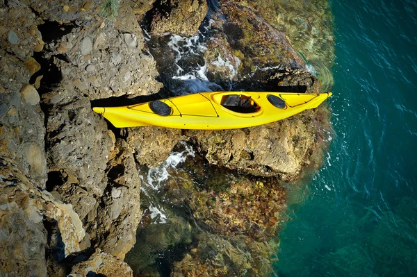 Yellow sea kayak beached on a rocky rapids