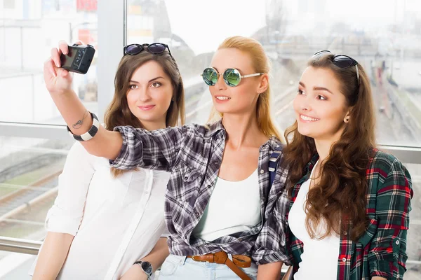 Three girls stand at the airport and looking at the tablet. A trip with friends.girls doing selfie