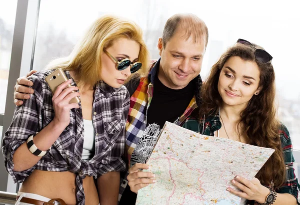 Young man and two women looking at a map. Europeans. Americans. Gathered in a guided tour. Close-up