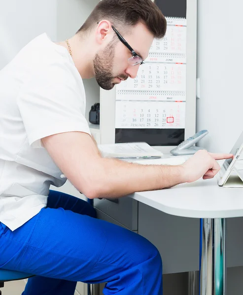 Healthcare, profession, stomatology and medicine concept - smiling male young dentist over medical office background