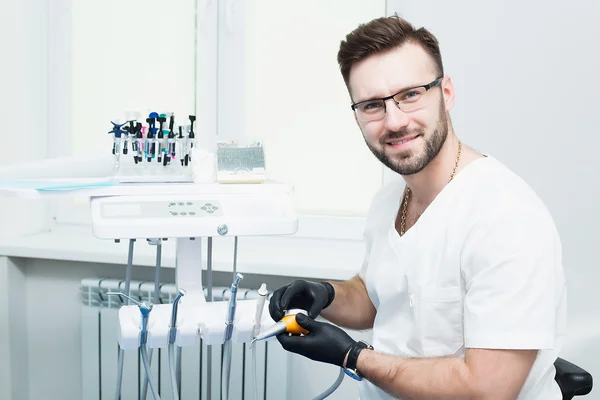 Healthcare, profession, stomatology and medicine concept - smiling male young dentist over medical office background