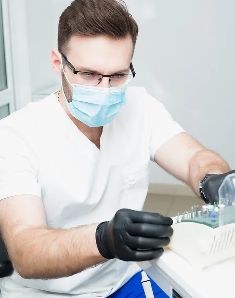 Healthcare, profession, stomatology and medicine concept - smiling male young dentist over medical office background