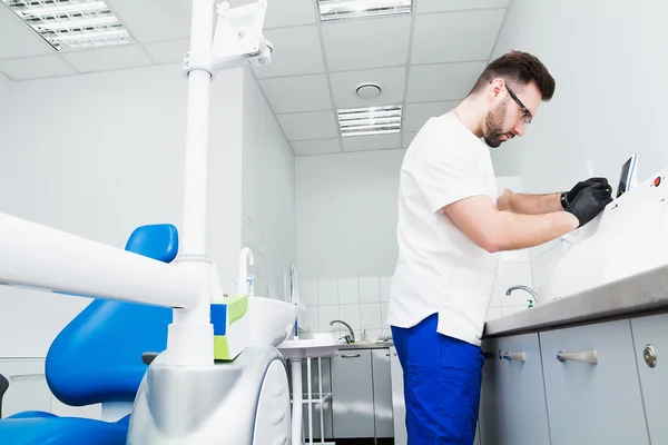 Healthcare, profession, stomatology and medicine concept - smiling male young dentist over medical office background