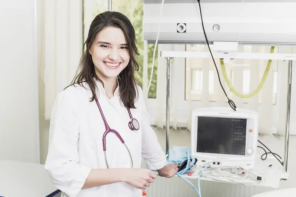 Girl Doctor in a white coat adjusts clinical equipment and monitor