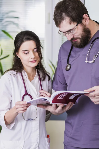 Girl Doctor in a white coat with a stethoscope and male doctor with book