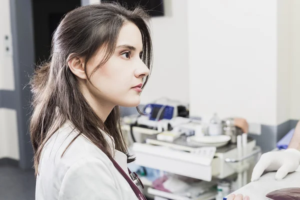 Girl Doctor in a white coat adjusts clinical equipment and monitor