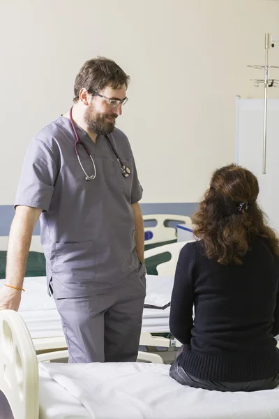 Bearded young doctor talks to a patient