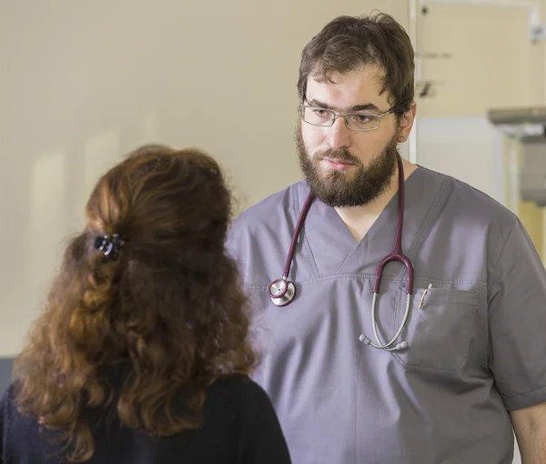 Bearded young doctor talks to a patient