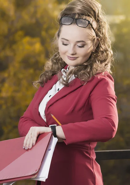 Smiling businesswoman studying the sketch of future business centre. Attractive lady in business suit is satisfied by the plan made by architect.