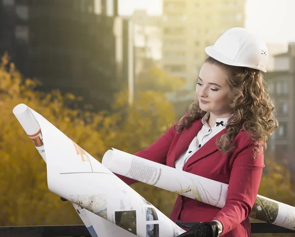 Smiling businesswoman studying the sketch of future business centre. Attractive lady in business suit is satisfied by the plan made by architect.