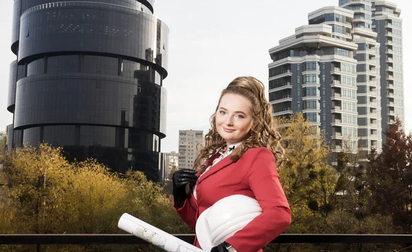 Smiling businesswoman studying the sketch of future business centre. Attractive lady in business suit is satisfied by the plan made by architect.