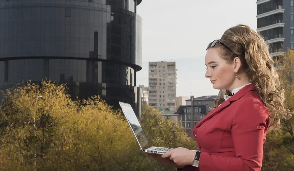 Smiling businesswoman studying a sketch of the future business center. An attractive woman in a business suit stands with computer