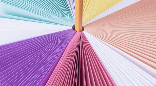 Colored paper for notes rainbow on a white table. White background. Orange pencil.