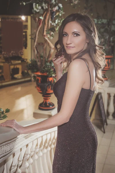 Beautiful elegant woman in a brown dress standing on vintage staircase in the castle