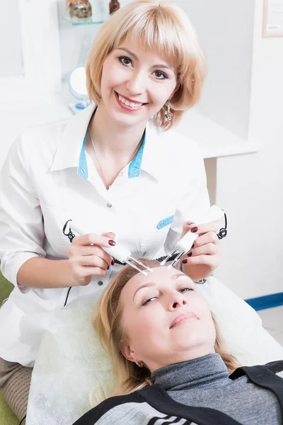 Beautiful girl beautician making permanent makeup on woman's face. Blonde. doctor.