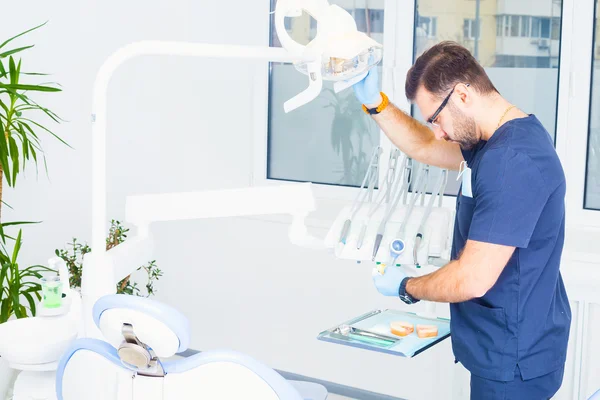 Healthcare, profession, stomatology and medicine concept - male dentist over medical office background
