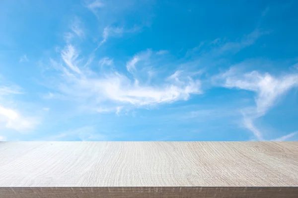 Top of wood table on soft blue sky background.