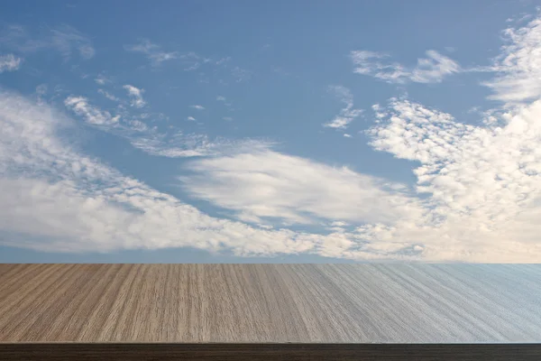 Top of wood table on soft blue sky background.