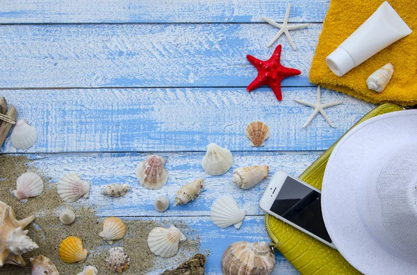 Summer beach sea concept. Blue Wooden background with different accessories, shells, starfish, towel, sunscreen, sand