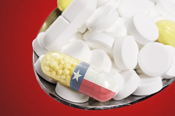Spoon full of pills and a capsule with the flagdesign of Texas.(