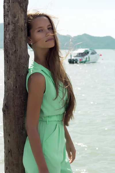 Beautiful tanned woman on pier in stylish elegant clothes poses enjoying amazing view. Fashion look. Phuket island, Thailand