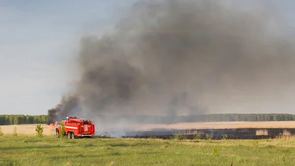 CHELYABINSK, RUSSIA - May 15, 2015: fire truck puts out in a field a forest fire fire truck puts out in a field a forest fire