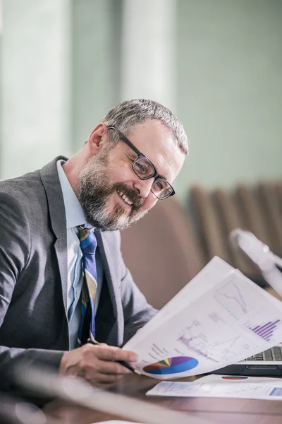 Bearded businessman reading business documents with charts