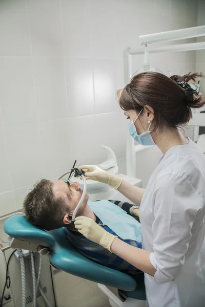 Dentist doctor puts on the patient dental front arc. the dentist is in the office beside the chair with the patient
