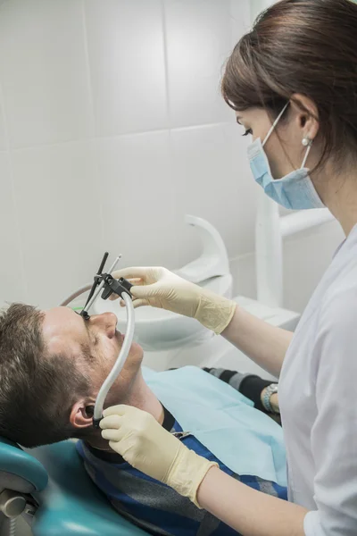 Dentist doctor puts on the patient dental front arc. the dentist is in the office beside the chair with the patient