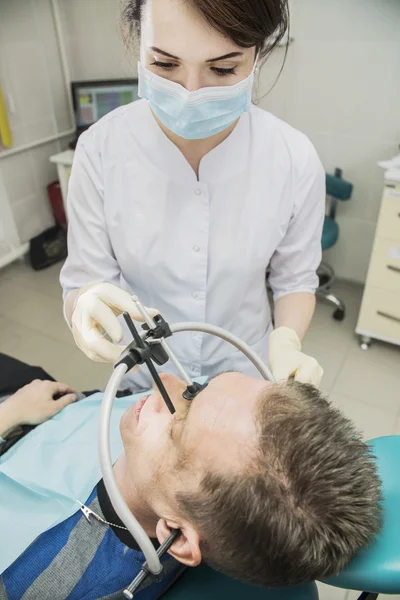 Dentist doctor puts on the patient dental front arc. the dentist is in the office beside the chair with the patient