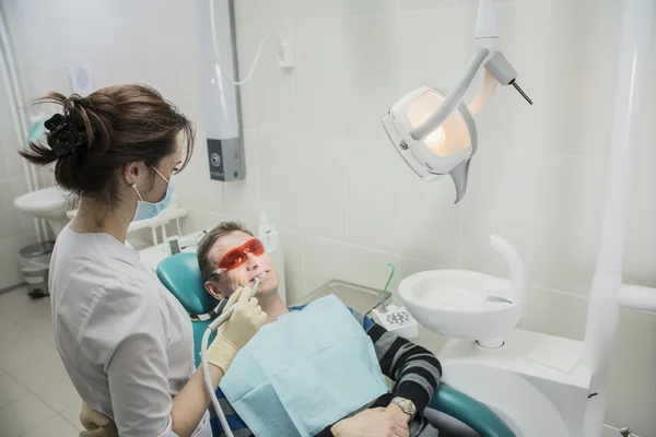 Dental care concept stomatology inspection. the patient lies in a chair in dentistry in front of him a hand with drill