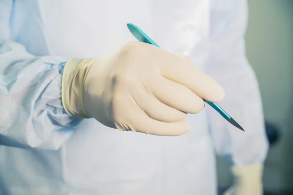 Closeup of a scalpel in hand on the background of the operating room