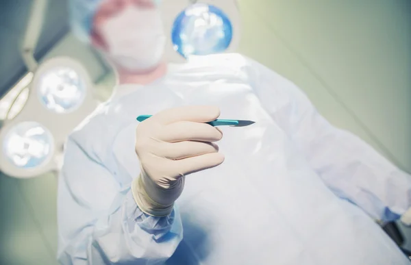 Closeup of a doctor holding a scalpel on the background of the operating room