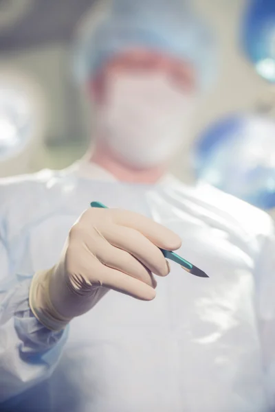 Closeup of a doctor holding a scalpel on the background of the operating room