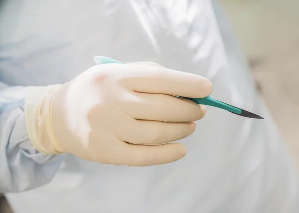 Closeup of a scalpel in hand on the background of the operating room