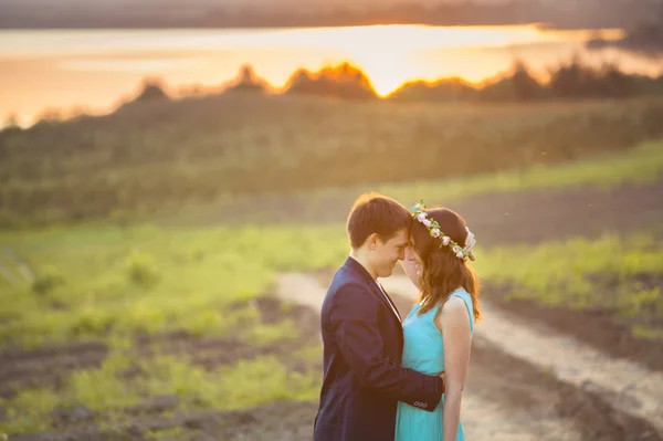 A Young couple in love outdoor at the sunset - looking at each other at the sunset background near the water