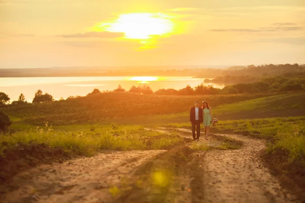 A Young couple in love outdoor at the sunset - enjoying the sunset in the meadow near the water