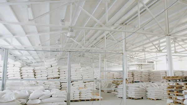 Bags with flour in warehouse of flour factory. Flour stock. Mill warehouse