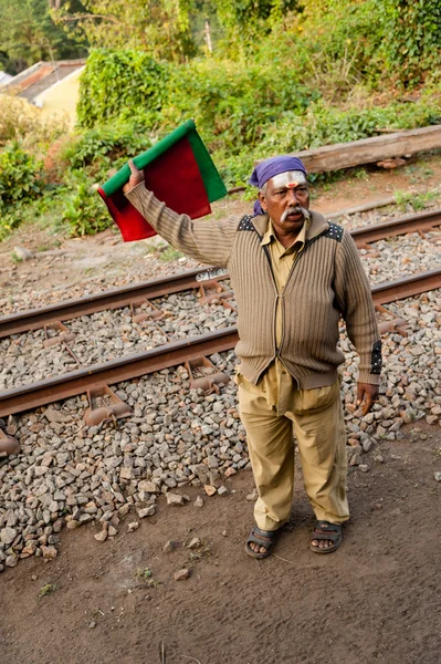 A railway worker with red and green flags