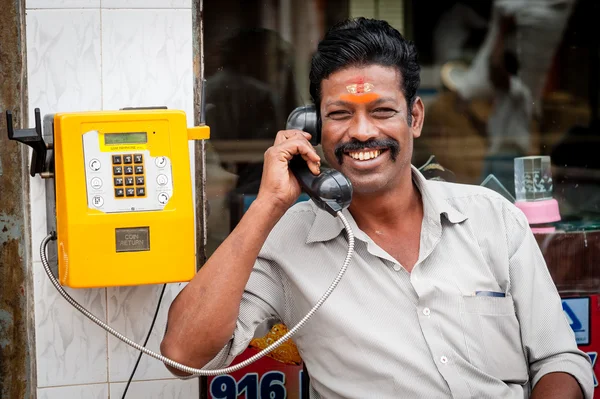 Indian man using a public telephone