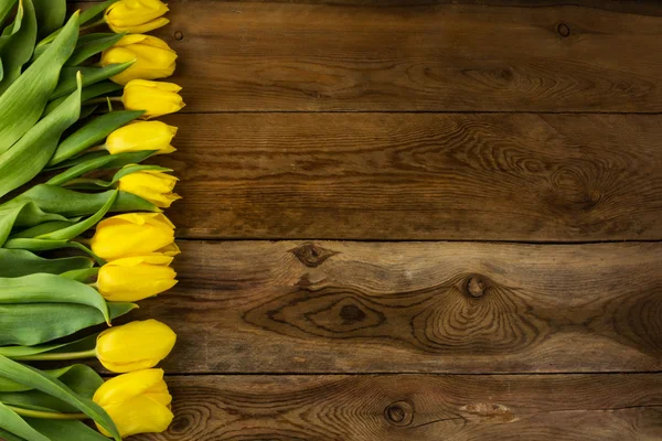 Yellow tulips bunch on wooden background