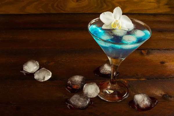 Blue cocktail served with orchid