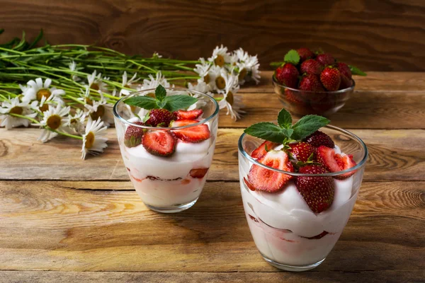 Layered strawberry yogurt dessert on wooden background