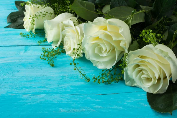 Ivory roses on wooden turquoise background