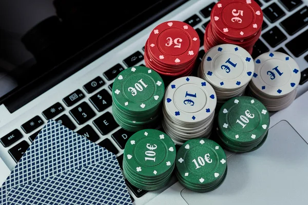 View of casino chips, cards on laptop to play online.