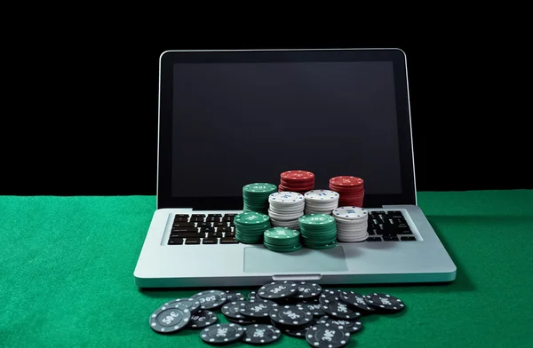 Casino chips on keyboard notebook at green table.