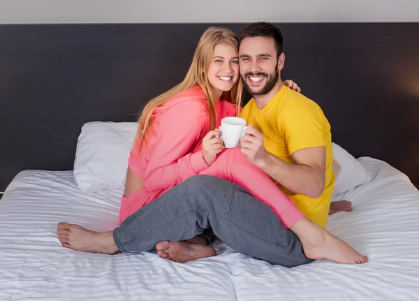Happy young couple having breakfast tray on bed at home