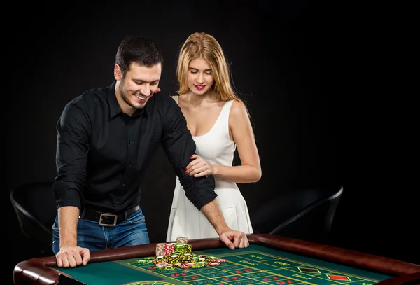 Young couple celebrating win at roulette table in casino.